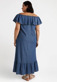 Maxikleid aus Denim mit schulterfreiem Rüschenausschnitt, gestuftem Saum und kurzen Ärmeln. Weicher Stoff, dunkelblaue Farbe und lockere Passform.