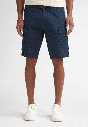 Marineblauwe cargoshorts van lichtgewicht stof, voorzien van zijzakken, lussen voor een riem en een ontspannen pasvorm, gecombineerd met witte sneakers.