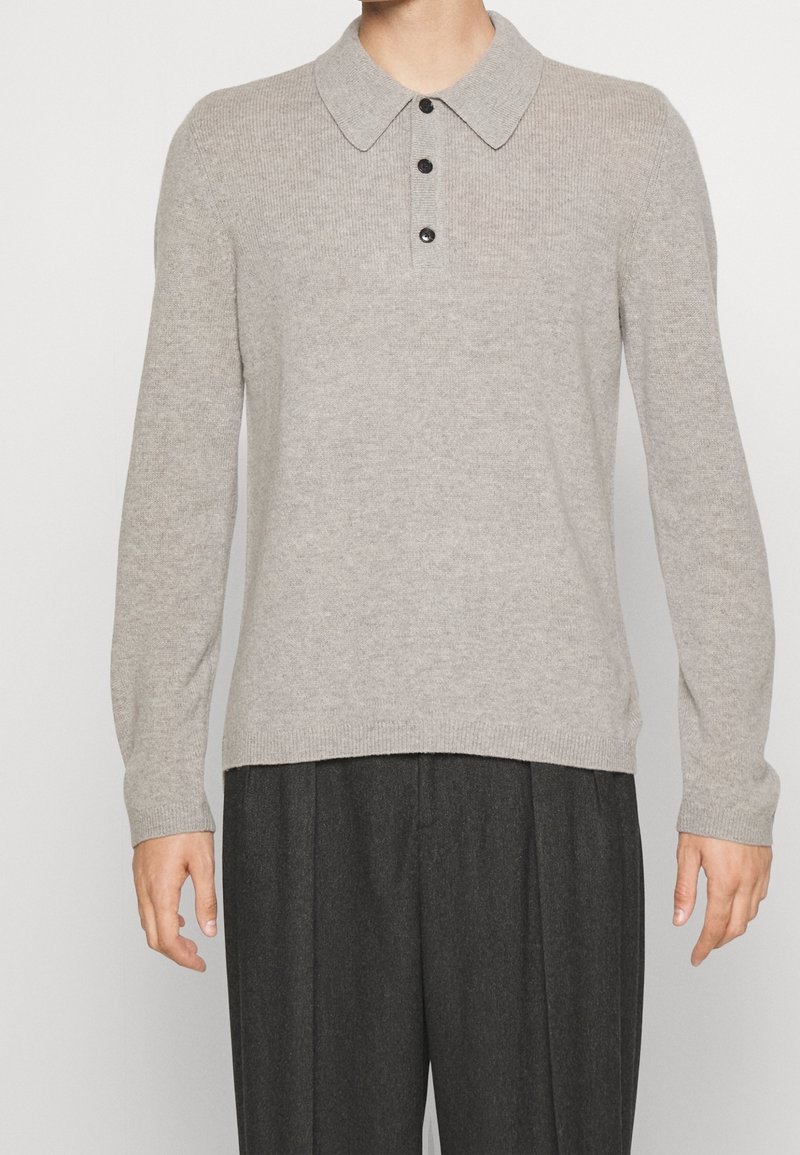 Pullover lavorato a maglia grigio chiaro con colletto, cinque bottoni neri e maniche lunghe. Presenta una texture a costine e una vestibilità morbida.