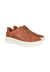 Zapatillas de cuero marrón con una suela de goma blanca, que cuentan con un diseño de cordones, detalles de costura y una marca en la lengüeta.