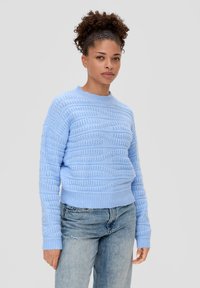 Lichtblauwe gebreide trui met een gestructureerd patroon, ronde halslijn en ribgebreide mouwen. Gecombineerd met lichtdenim jeans.