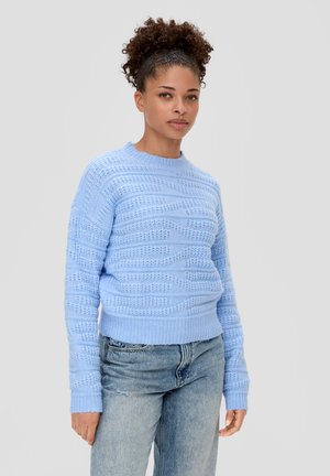 Light blue knitted sweater with a textured pattern, round neckline, and ribbed cuffs. Paired with light denim jeans.