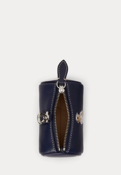 Navy blue cylindrical pouch with top zipper slightly open, beige interior lining, silver clasp, and a small teddy bear embroidery on the side.