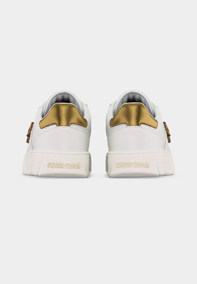 Ζευγάρι λευκών χαμηλών αθλητικών παπουτσιών με χρυσές λεπτομέρειες στο τακούνι και ανάγλυφη επωνυμία «roberto cavalli» στη φτέρνα, σε θέα από πίσω.