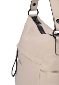 Bolso de hombro de cuero beige con cierre de cremallera, bolsillo lateral y herrajes en negro contrastante. Presenta una textura suave y detalle de logo.