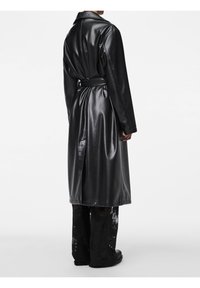 Manteau en simili cuir noir avec col, manches longues et ceinture à la taille. Présente une texture lisse et une coupe longue avec une fente à l'arrière.
