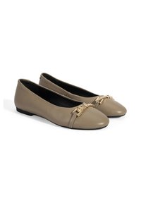 Beige Leder Ballerinas mit einer runden Zehenpartie und einer dekorativen Hardware-Akzent in goldfarbener Ausführung über der Vorderseite. Flache Sohle, glatte Textur.