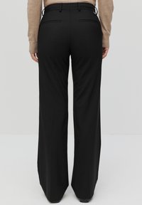 Vida svarta byxor med vida ben och en slät yta, som har två bakfickor och en midjeresår. Tyget är lätt och designat för komfort.