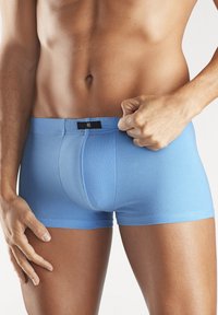 Hellblaue Baumwoll-Boxershorts mit enger Passform, ausgestattet mit einem schwarzen Markenetikett am Bund und einer glatten Textur.