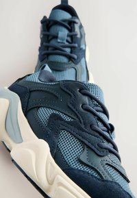 Baskets de sport bleues en mesh et suède, avec un design texturé, une semelle rembourrée et des lacets tissés.