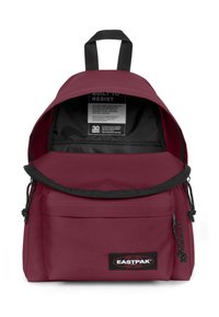 Mochila Eastpak color burdeos con cierre de cremallera, correas ajustables, bolsillo frontal y una etiqueta negra. El texto interior dice "CONSTRUIDA PARA RESISTIR."