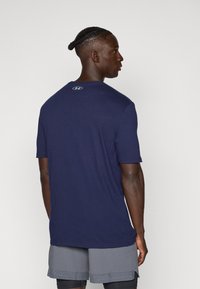 Navy blue short-sleeve t-shirt made from soft fabric, features a crew neckline and small logo accent at the back near the collar.