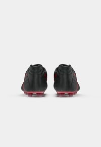 Crampos de futebol pretas com detalhes em vermelho. Material sintético suave, bico arredondado e suporte texturizado no calcanhar. Sola transparente com cravos.