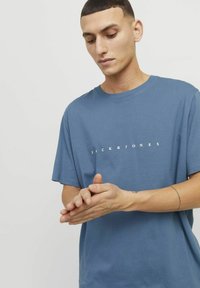 Kurzarm-T-Shirt mit Rundhalsausschnitt aus weichem blauen Stoff. Mit weißem "JACK & JONES"-Druck auf der Brust. Schmale Passform, minimalistisches Design.