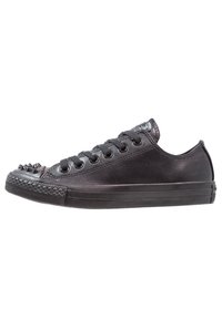 Black leather sneaker with a low profile, round toe, and spiked accents on the toe cap. Features six pairs of eyelets and a textured sole.