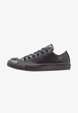 Black leather sneaker with a low profile, round toe, and spiked accents on the toe cap. Features six pairs of eyelets and a textured sole.