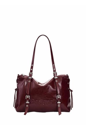 Borsa a mano in pelle rosso scuro con fibbie argentate, doppi manici a spalla, lacci laterali e logo Desigual in rilievo sul davanti.
