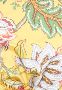 Tecido floral com fundo amarelo, apresentando flores vermelhas, rosas e verdes, folhas intrincadas e uma textura suave e macia.