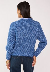 Maglione blu lavorato a maglia con un design testurizzato, orlo a coste e maniche lunghe. Presenta un colletto bianco e smerigliature multicolori.