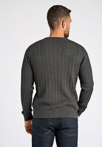 Tummanharmaa cable-knit neulepaita, jossa on ribbaus hihansuissa ja helmassa. Siinä on tekstuurinen kuvio ja pyöreä kaula-aukko, rento malli.