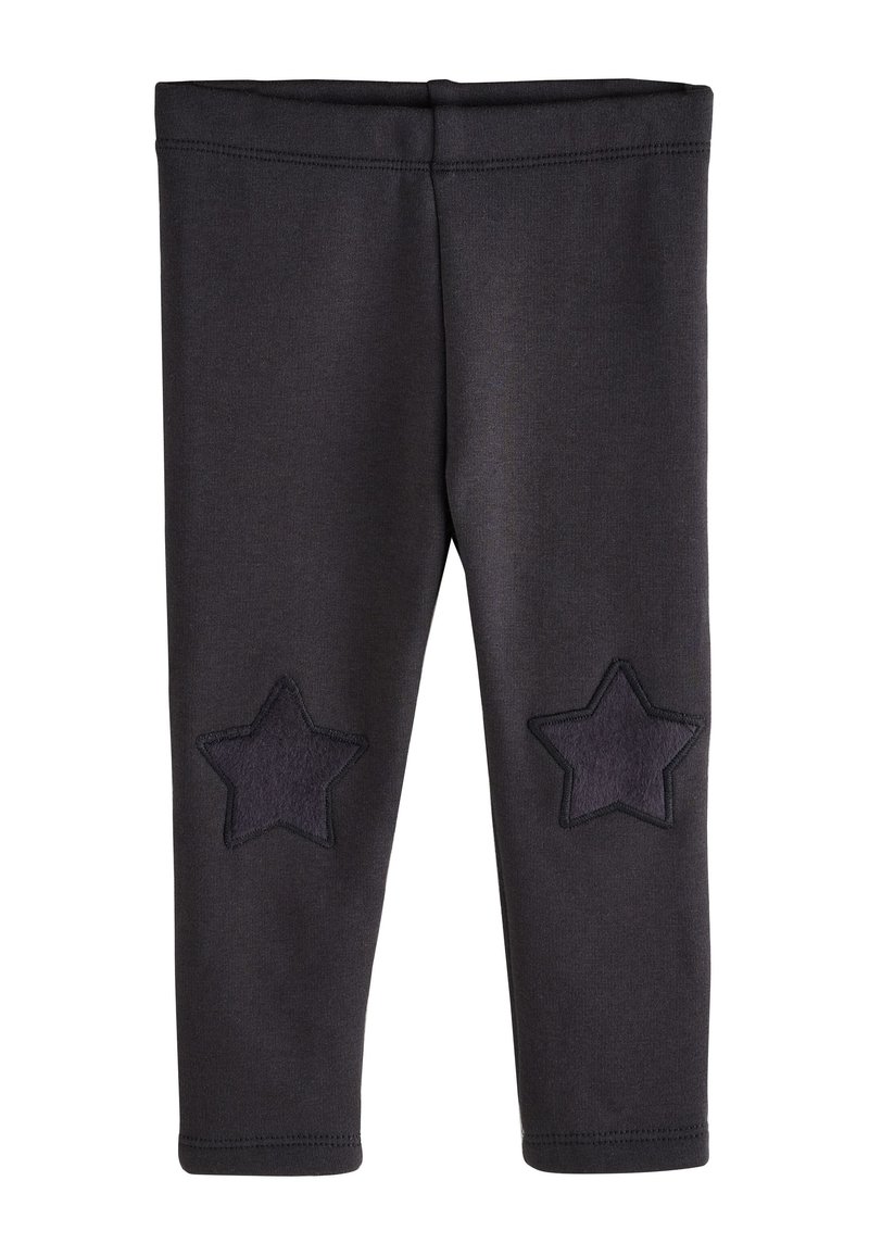 Leggings negras de tela suave, con dos apliques de estrellas oscuras en las rodillas. La cintura es elástica y las costuras están reforzadas.