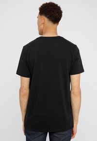 Svart bomulls t-shirt med korta ärmar och rundhals, med en slät textur och rak nederkant, visad bakifrån.