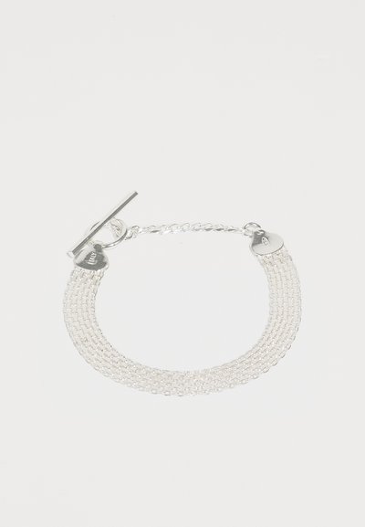 Sølv armbånd i kæde, der har flere sammenkoblede strenge, en toggle-lukning og en hjerteformet charme med branddetalje.