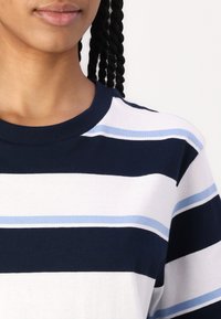 Navy and white striped t-shirt with light blue accents. Short sleeves, round neckline, soft cotton material, horizontal stripes of varying widths.