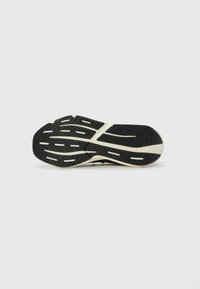 Semelle de chaussure de sport en caoutchouc noir avec un motif texturé, présentant des rainures et des accents blancs pour améliorer l'adhérence et la stabilité.