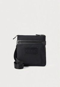 Fekete nejlon keresztpántos táska elülső cipzáras zsebbel, logó rátéttel és állítható pánttal, amely ismétlődő márkajelzést visel. Sima textúra, kompakt kialakítás.