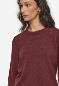 Burgunderfarbener Wollpullover mit Rundhalsausschnitt und langen Ärmeln, der eine weiche Textur und eine lässige Passform aufweist.
