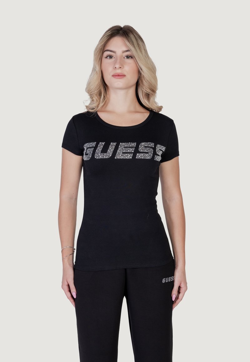 Musthave mustaga t-särk lühikeste varrukatega, millel on rinnas "GUESS" rhinestone'idega, sile kangas ja ümmargune kaelus.