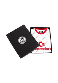 Witte voetbalshirt met rode kraag, voorzien van een diagonaal lijnpatroon en rode tekst "Commodore" en logo van FC Bayern München, gepresenteerd in een zwart vak.