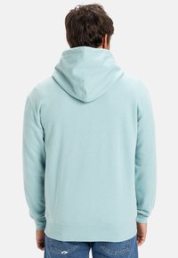 Light blue hoodie made of soft fabric. Features a drawstring hood, long sleeves, and a ribbed hem, with a smooth texture.