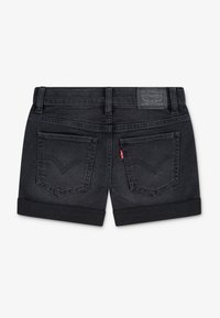 Μαύρα σορτς από τζιν με γιακάδες γυρισμένους προς τα πάνω, με δύο πίσω τσέπες που φέρουν το χαρακτηριστικό ραφτό σχέδιο και μια ετικέτα με το λογότυπο της Levi's στη μέση της ζώνης.