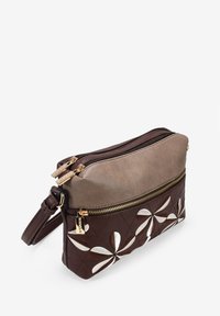 Bolso cruzado de cuero marrón y topo con diseño acolchado, cremalleras doradas y acentos florales en plata. Incluye una correa ajustable.