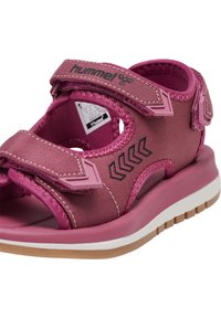 Różowe sandały wykonane z teksturowanego materiału syntetycznego, z regulowanymi paskami, gumową podeszwą oraz wzorem chevron po boku.