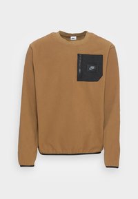 Brun fleece-tröja med en svart bröstficka med blixtlås, försedd med en logotypmärke. Rundad halsringning och elastiska muddar.