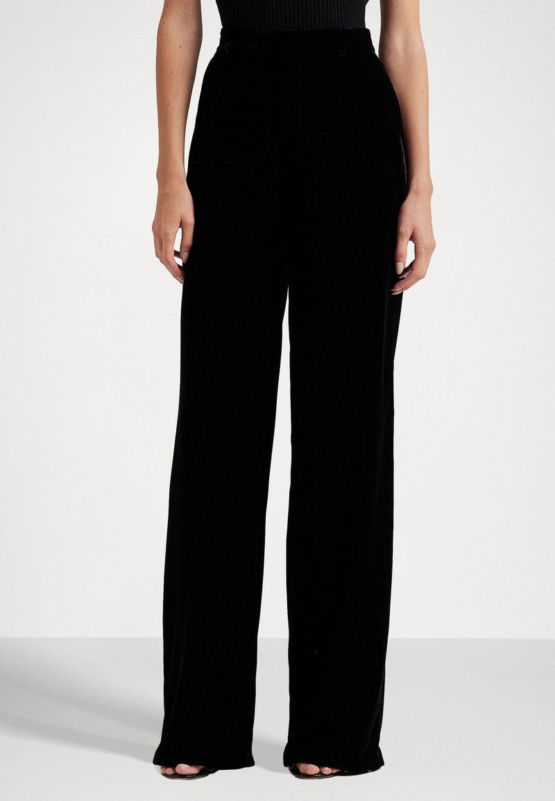 Pantalons larges noirs en velours lisse, taille haute et boucles de ceinture discrètes. Dotés d'une coupe classique et d'un design longueur totale.
