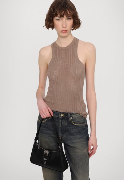 Strikket tank topp i lys brun med høy hals og strukturert mønster, kombinert med løse, mørk denim jeans og en svart håndveske med en sølvspenne.