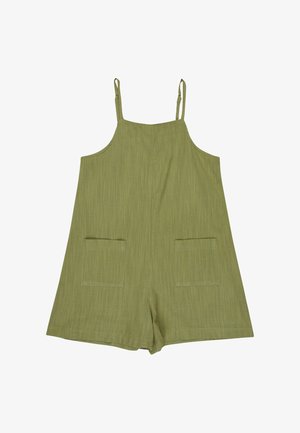 Vestido verde de algodón tipo peto con dos bolsillos delanteros, llevado sobre una camiseta de manga larga a rayas blancas y negras, combinado con una gorra rosa.