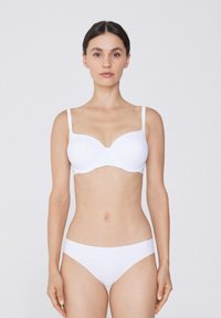 Ein weißer BH und passende Unterwäsche verfügen über eine glatte Textur, halbpadded Cups und dünne verstellbare Träger, die für einen nahtlosen Look sorgen.