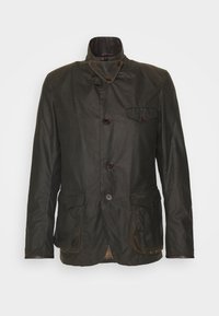 Dark green waxed cotton jacket with a high collar, double-breasted buttons, chest pocket, and plaid lining. Features two front pockets.