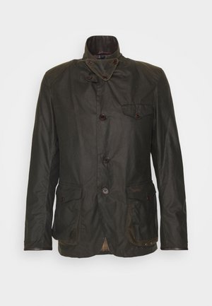 Dark green waxed cotton jacket with a high collar, double-breasted buttons, chest pocket, and plaid lining. Features two front pockets.