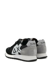 Zapatillas en negro y gris con una parte superior de ante y malla, presentan un diseño de logo blanco en el costado y una suela de goma negra.