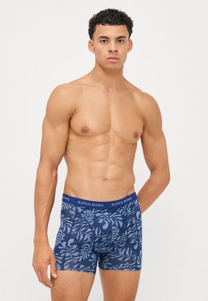 Boxer-briefs bleu marine avec un motif de feuilles, texture en mesh, et une taille élastique arborant le nom de la marque "BJÖRN BORG" en lettres blanches.