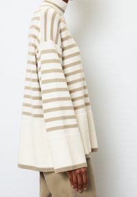 Creme- und beiger gestreifter Pullover mit hohem Kragen, weiter Passform, gerippten Bündchen und Saum; aus weichem Strickmaterial gefertigt.