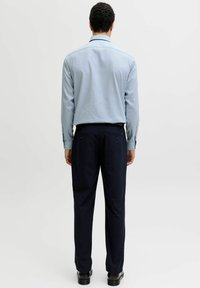 Hele sinine, triibuline pikkade varrukatega särk koos tumesiniste, kohandatud pükstega, vaadatuna tagantpoolt, esitades puhta ja vabaaja stiili.