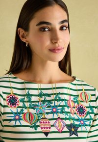 Pruhovaný svetr v krémové a zelené barvě s propracovanou vánoční výšivkou, která zobrazuje ozdoby, hvězdy a listoví v živých barvách.