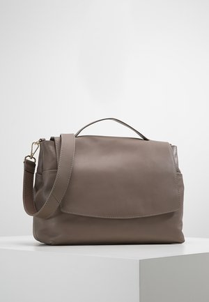 Sac à bandoulière en cuir taupe avec poignée supérieure, fermeture à rabat et sangle réglable, présenté sur une surface blanche avec un fond uni.